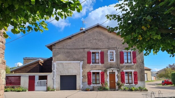 A two-story house with a garage, a red door, and a small porch area. - 3-bedroom/two-bathroom house in the countryside (Bezange-la-Grande)