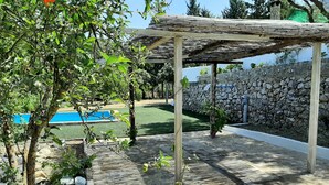 Un muro in pietra, un pergolato e una zona piscina.