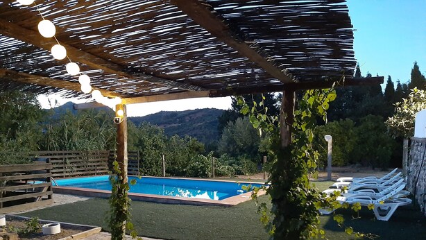 Area piscina con pergola, circondata da vegetazione e con vista sulle montagne.