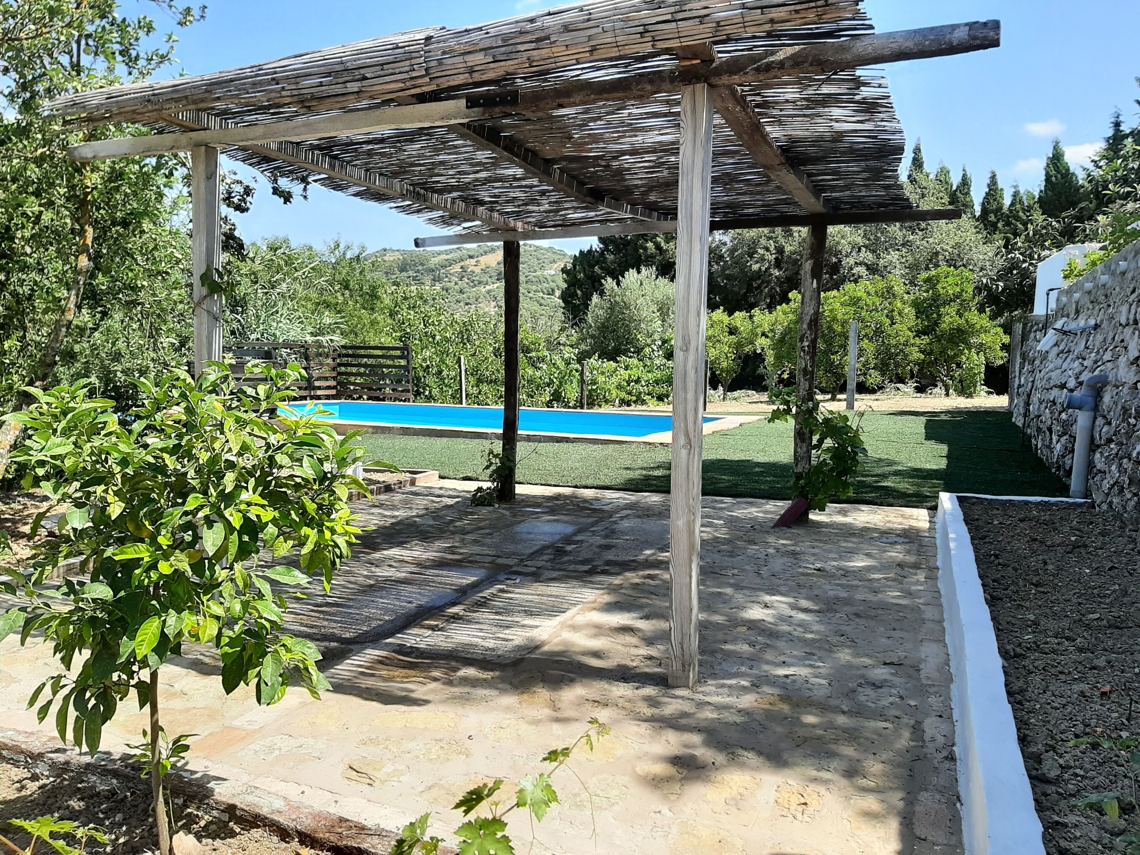 Un espace extérieur abrité, doté d’une piscine, entouré de verdure et de murs en pierre.