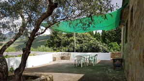 Un'area patio con pareti in pietra, una tenda da sole verde e un tavolo con sedie.