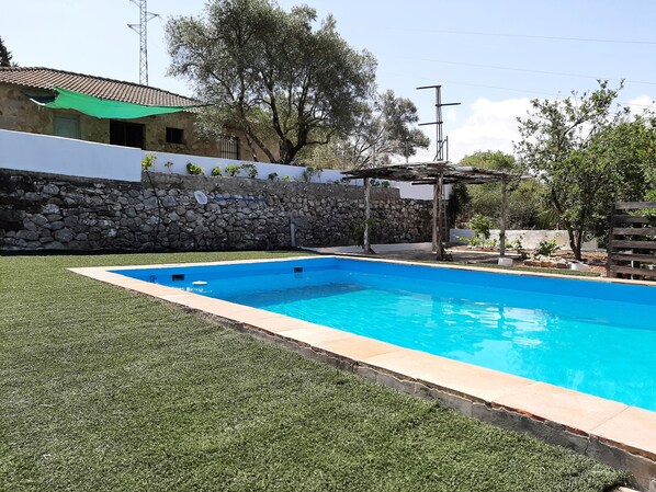 Une piscine avec un mur en pierre et une pergola.