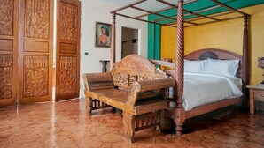 A four-poster bed with a wooden canopy, a wooden bench, and intricately carved doors. - Villa Himala Bali (Seminyak)