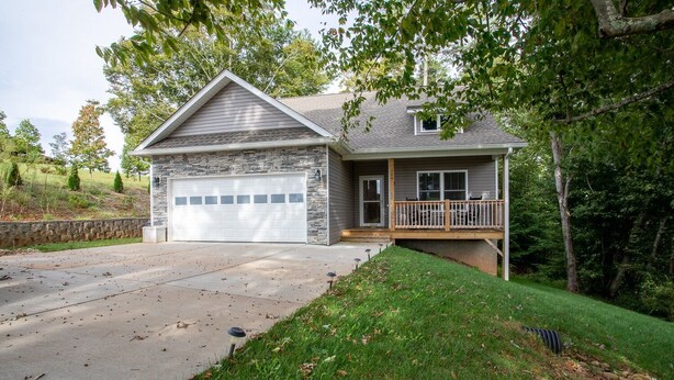 A two-story house with a stone facade, a garage, and a covered porch. - The Hidden Gem | A Luxury Mountain Getaway (Weaverville)