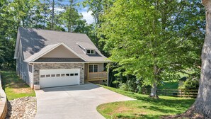 A single-story house with a garage, a front porch, and a driveway leading to the garage. - The Hidden Gem | A Luxury Mountain Getaway (Weaverville)