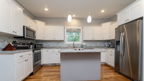 A modern kitchen with white cabinets, stainless steel appliances, and a central island. - The Hidden Gem | A Luxury Mountain Getaway (Weaverville)