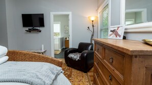 A bedroom with a bed, a chair, a dresser, a television, and a window with blinds. - The Hidden Gem | A Luxury Mountain Getaway (Weaverville)