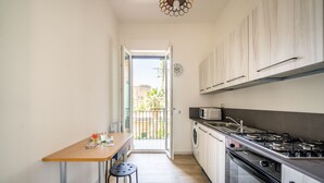 A narrow kitchen with a dining area, a washing machine, and a stove. - Un Balcone sull'Orto Botanico by Wonderful Italy (Palermo)