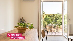 A modern room with a wooden table, a wicker basket with plants, and a view of a balcony with outdoor furniture. - Un Balcone sull'Orto Botanico by Wonderful Italy (Palermo)