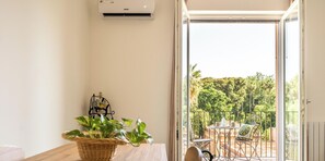 Ein modernes Zimmer mit einem Holztisch, einem Korbwicker-Korb mit Pflanzen und Blick auf einen Balkon mit Gartenmöbeln.