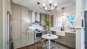 A modern kitchen with white cabinetry, a central island, and a chandelier. - Hip and Historic Home Awaits You!  Stroll downtown/Steps away from UCA and CBC (Conway)