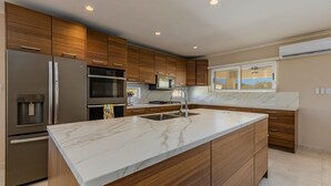 Une cuisine moderne avec des meubles en bois, des appareils en acier inoxydable et un plan de travail en marbre.