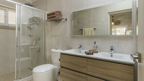 Une salle de bain moderne avec une douche à parois de verre, des toilettes, un lavabo avec un miroir et des meubles en bois.
