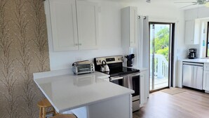 Una cocina moderna con una isla central, muebles blancos y vistas al exterior.