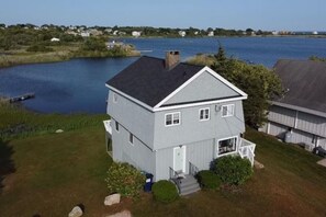 A two-story house with a gabled roof, a front porch, and a small deck.