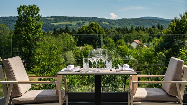 A table set for two with a scenic view of a forested landscape. - Hotel Palcich (Rakovica)