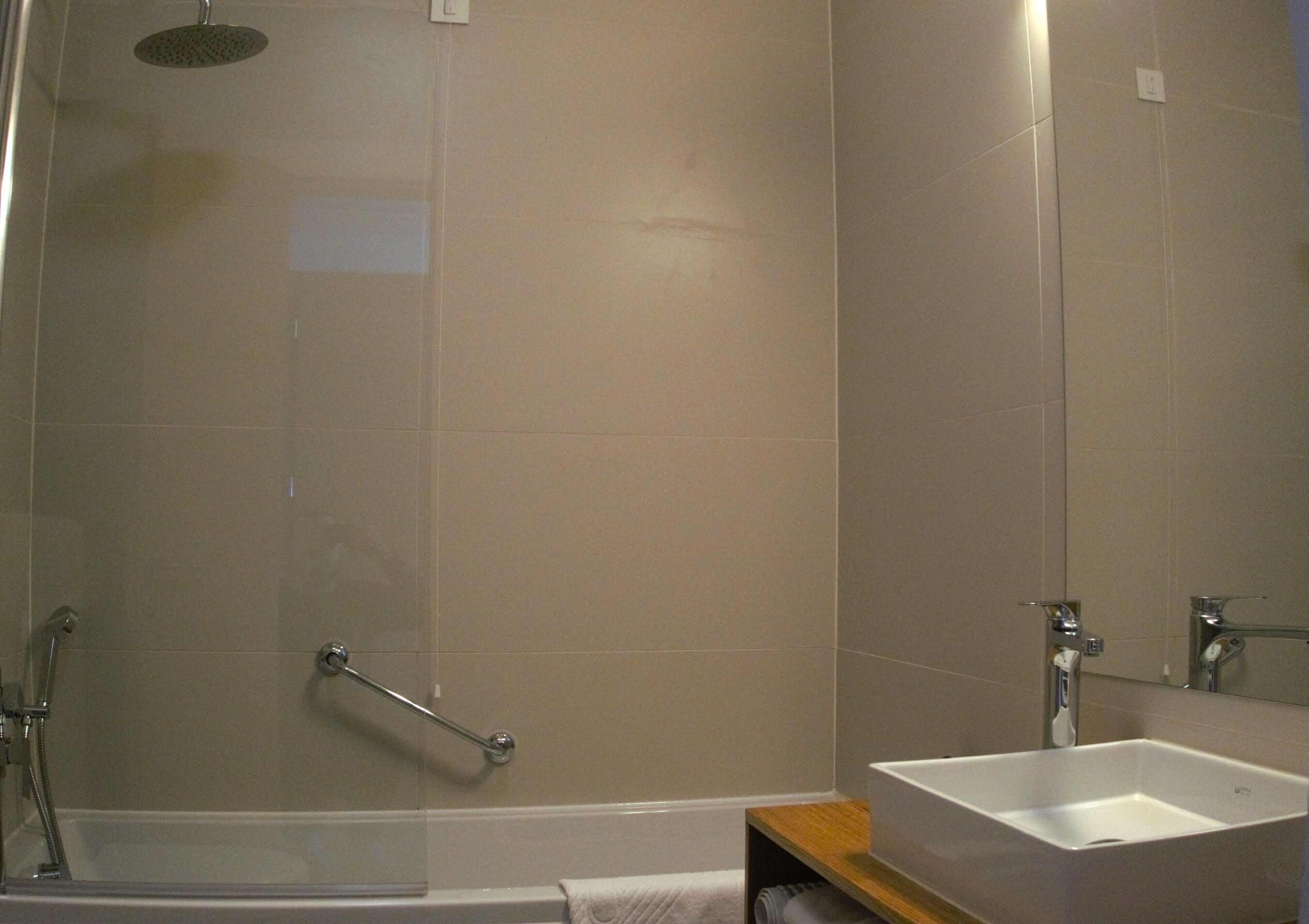 Une salle de bain moderne équipée d’une douche, d’un lavabo et d’un miroir.