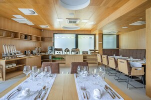 Un restaurante moderno con interiores de madera, varias mesas dispuestas con manteles blancos y una variedad de cristalería y cubiertos.