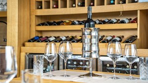A wine tasting setup with a bottle of wine, six glasses, and a wine rack in the background. - Hotel Palcich (Rakovica)