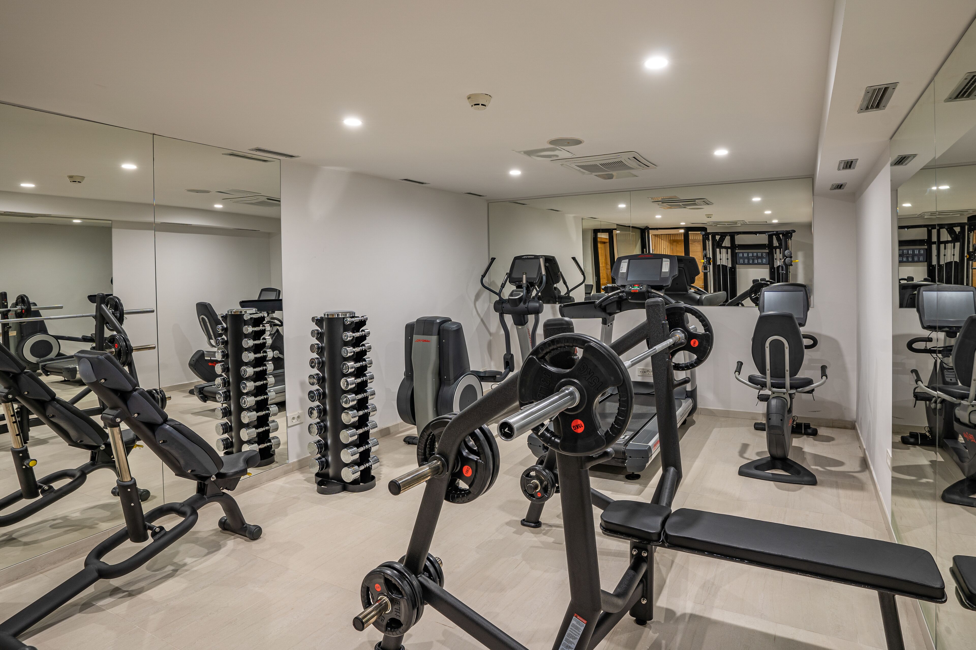 Et fitnesscenter med forskellig træningsudstyr, herunder styrkemaskiner, løbebånd og håndvægte.