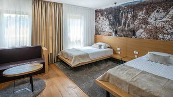 Une chambre d’hôtel avec deux lits, un canapé, une petite table et une grande fresque murale.
