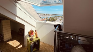 A room with a skylight, a small table with decorative items, and a view of a marina. - ❤️ New! Luxury apartment with sea view in the heart of downtown (Concarneau)