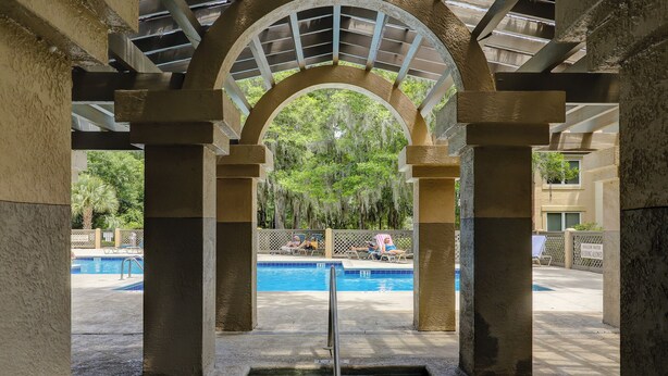Área de hidromassagem com piscina ao fundo, cercada por colunas e uma galeria coberta.