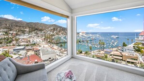 A room with a large bay view, a grey sofa, and a small rug.