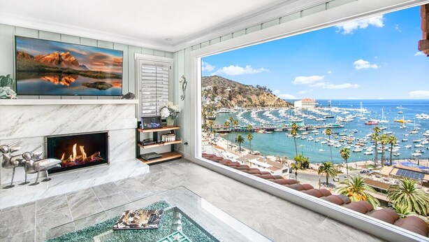 A spacious living room with a large bay window overlooking a marina and ocean.