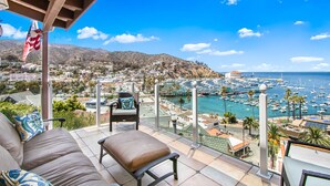 A balcony with a view of a marina and a hillside town.