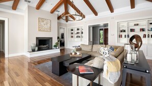 Amplia sala de estar con chimenea, un sofá grande, una mesa de centro y una estantería.