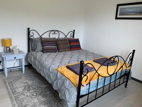 A neatly arranged bedroom with a bed, bedside table, and a rug.