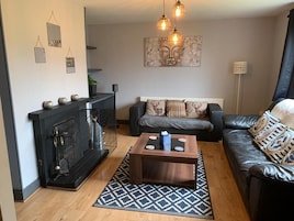 Una sala de estar con chimenea, un sofá, una mesa de centro y una obra de arte colgada en la pared.