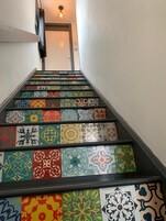 Una escalera con baldosas de colores y diseños que llevan a una puerta.