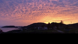A coastal landscape with a sunset, houses, and a body of water. - The Rabbit Hole - Kinlochbervie (Kinlochbervie)