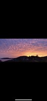 Paisaje costero con atardecer, casas y una masa de agua.