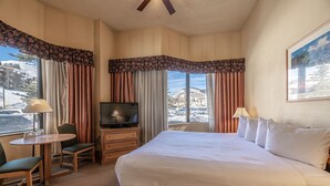 A hotel room with a large bed, a desk with a chair, a television, and a window with curtains. - Cozy Pet-friendly King Studio In Mt. Crested Butte Condo - No Cleaning Fee! by RedAwning (Crested Butte)