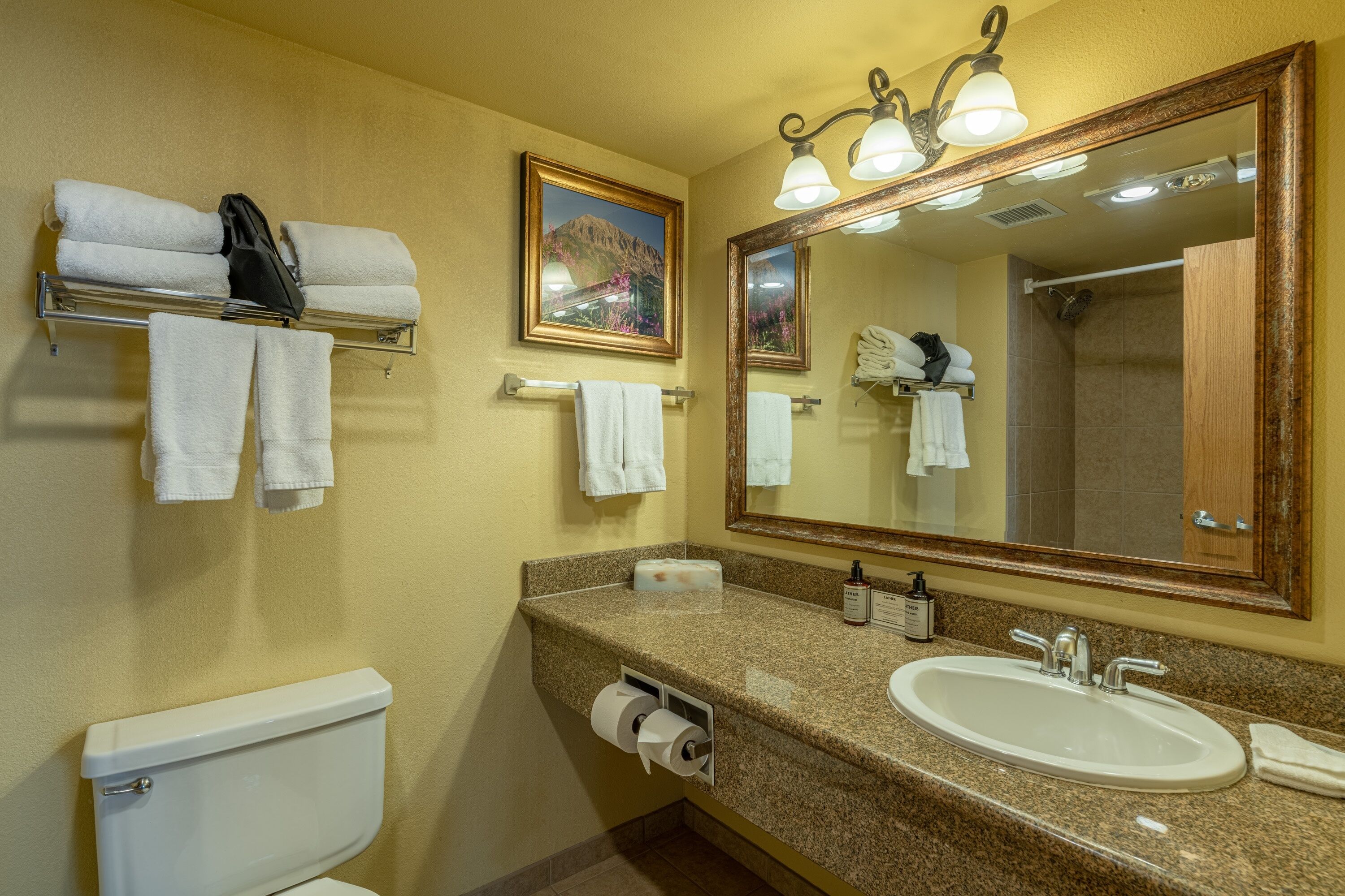 A bathroom with a toilet, sink, towel rack, and a large mirror.