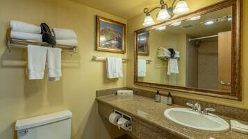 A bathroom with a toilet, sink, towel rack, and a large mirror.