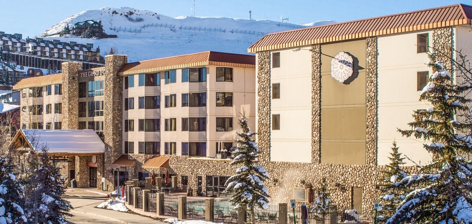 Hotel com vários andares, fachada de pedra e um relógio na frente.