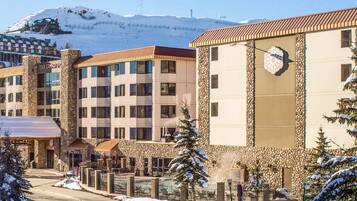 Hotel com vários andares, fachada de pedra e um relógio na frente.