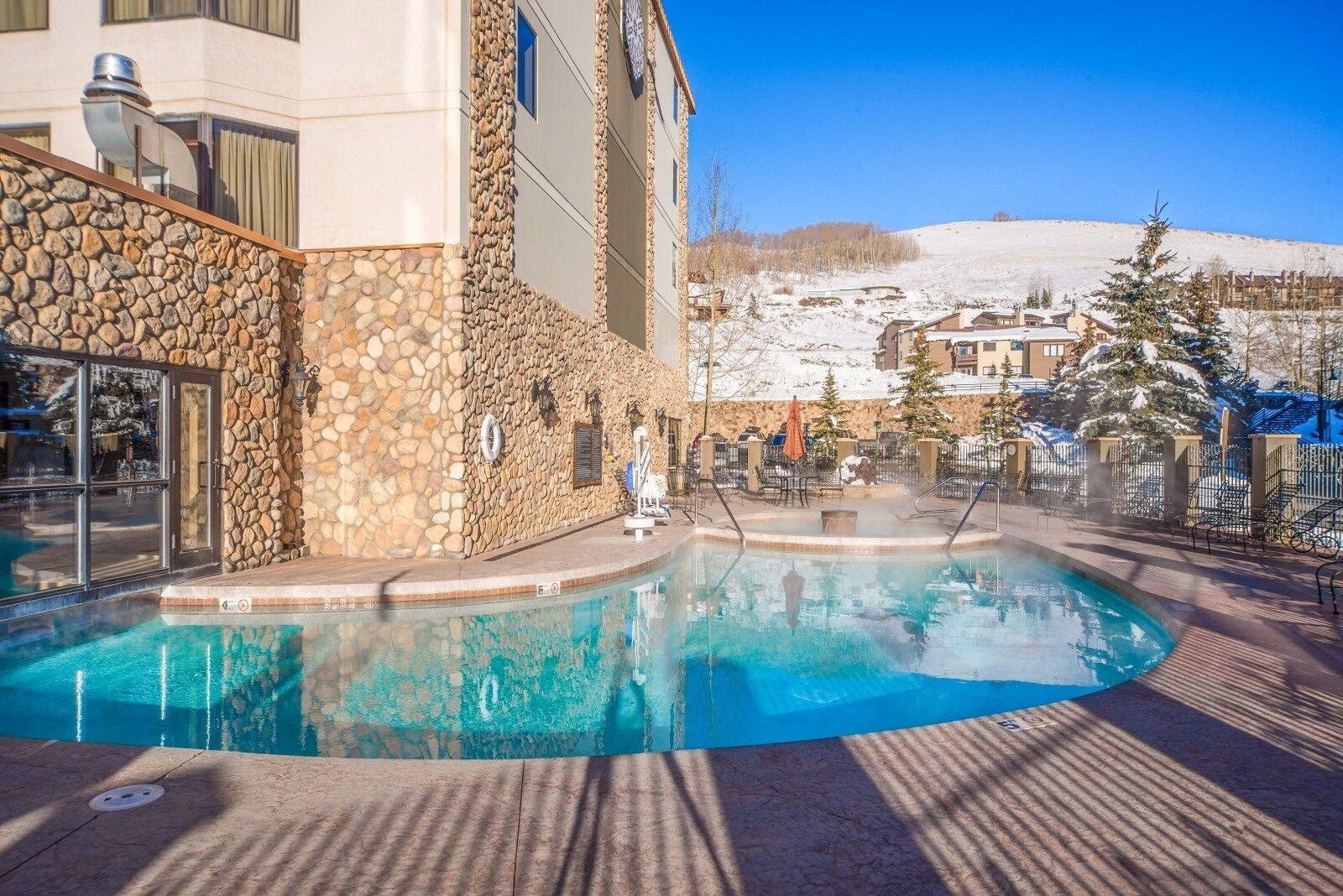 A pool area with a stone wall and a view of a snowy landscape.