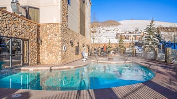 A pool area with a stone wall and a view of a snowy landscape.