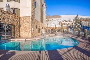 A pool area with a stone wall and a view of a snowy landscape. - Grand Lodge Condo In The Heart Of Mt Crested Butte 1 Bedroom Condo - No Cleaning Fee! by RedAwning (Crested Butte)