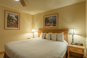 A neatly made bed with white linens, two bedside tables with lamps, and two framed landscape paintings on the walls. - Grand Lodge Condo In The Heart Of Mt Crested Butte 1 Bedroom Condo - No Cleaning Fee! by RedAwning (Crested Butte)