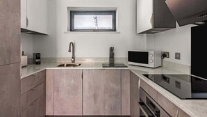Una cocina moderna con ventana sobre el lavamanos, electrodomésticos integrados y un diseño de encimera elegante.