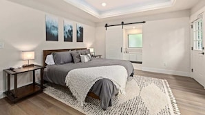 A bedroom with a bed, nightstands, a ceiling fan, artwork on the wall, and a sliding door to the bathroom. - OZ Adventure Retreat-Explore *Ride*Relax*Repeat (Bella Vista)