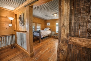 A rustic wooden room with a bed, a lamp, and a window. - Escape to Calcasieu Lake Lodge-Premier Fishing and Family Getaway (Lake Charles)