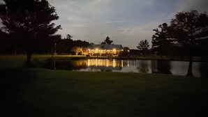 A lakeside building with a reflection in the water, surrounded by trees. - Escape to Calcasieu Lake Lodge-Premier Fishing and Family Getaway (Lake Charles)