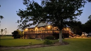 A two-story wooden house with a covered porch and a staircase leading to the upper level. - Escape to Calcasieu Lake Lodge-Premier Fishing and Family Getaway (Lake Charles)